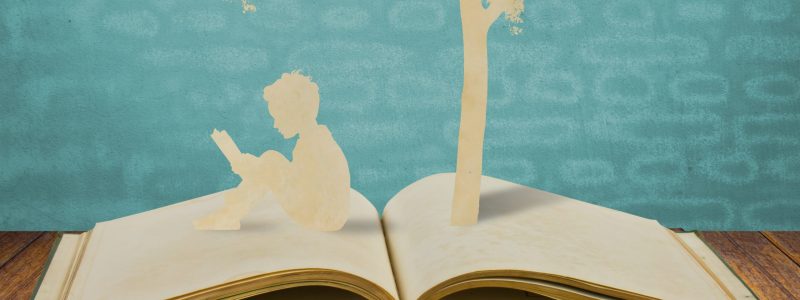 Paper cut of children read a book under tree on old book